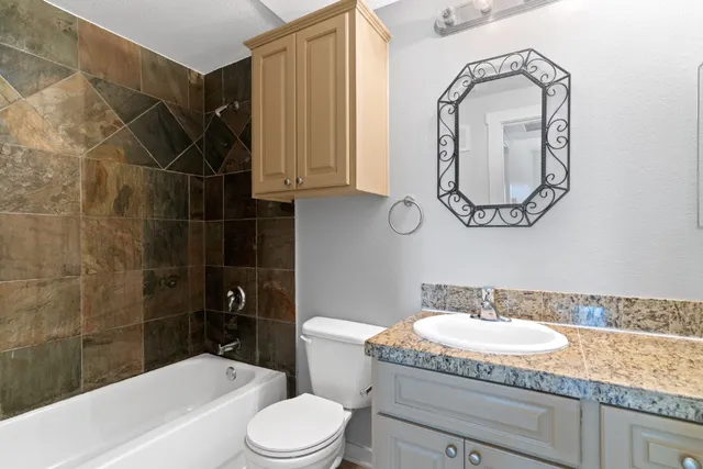 a bathroom with a granite countertop sink toilet and shower