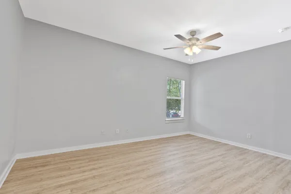 an empty room with a window and a fan