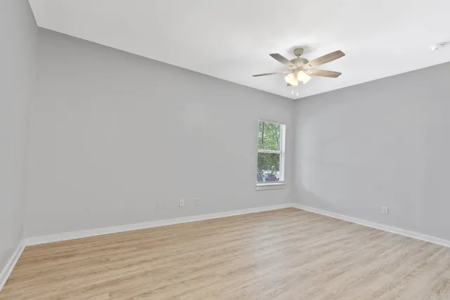 an empty room with a window and a fan