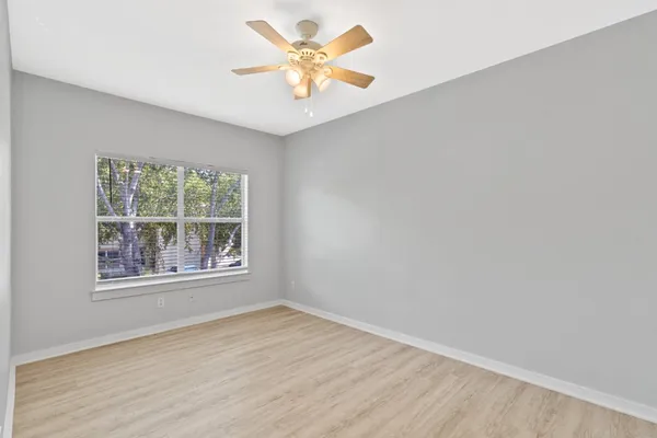 an empty room with a window and a fan