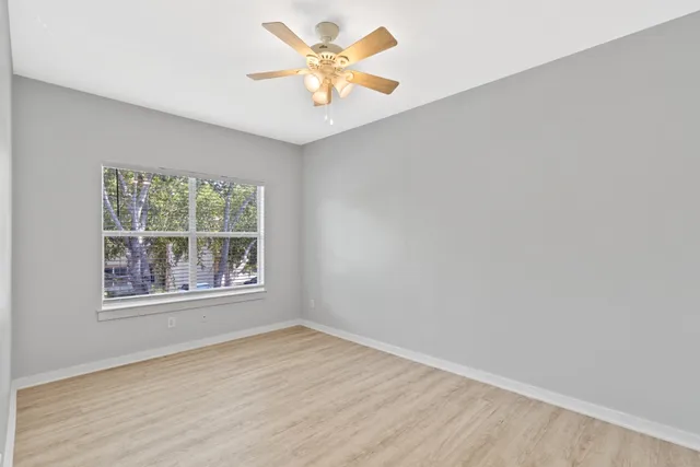 an empty room with a window and a fan