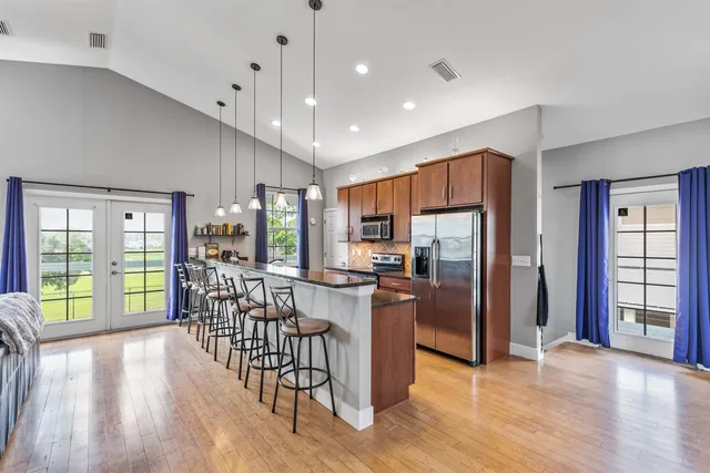 a kitchen with granite countertop stainless steel appliances a refrigerator a stove top oven and a dining table with wooden floor