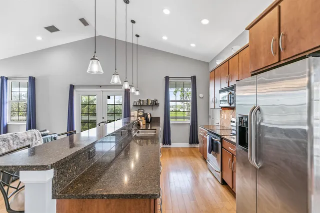 a kitchen with stainless steel appliances granite countertop a refrigerator oven stove top oven with a dining table and chairs