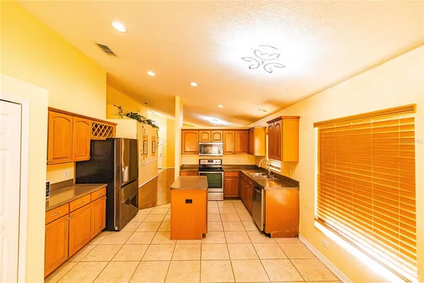 a kitchen with stainless steel appliances kitchen island granite countertop a refrigerator and cabinets