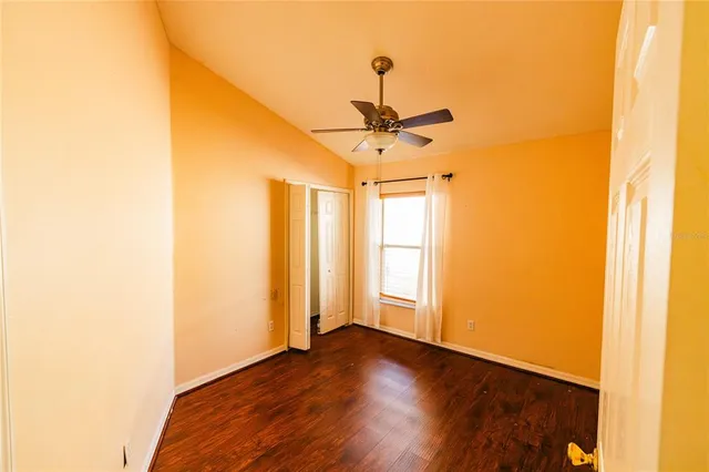 a view of empty room with wooden floor and fan