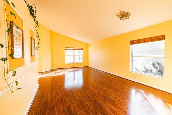 a view of an empty room with a window and wooden floor