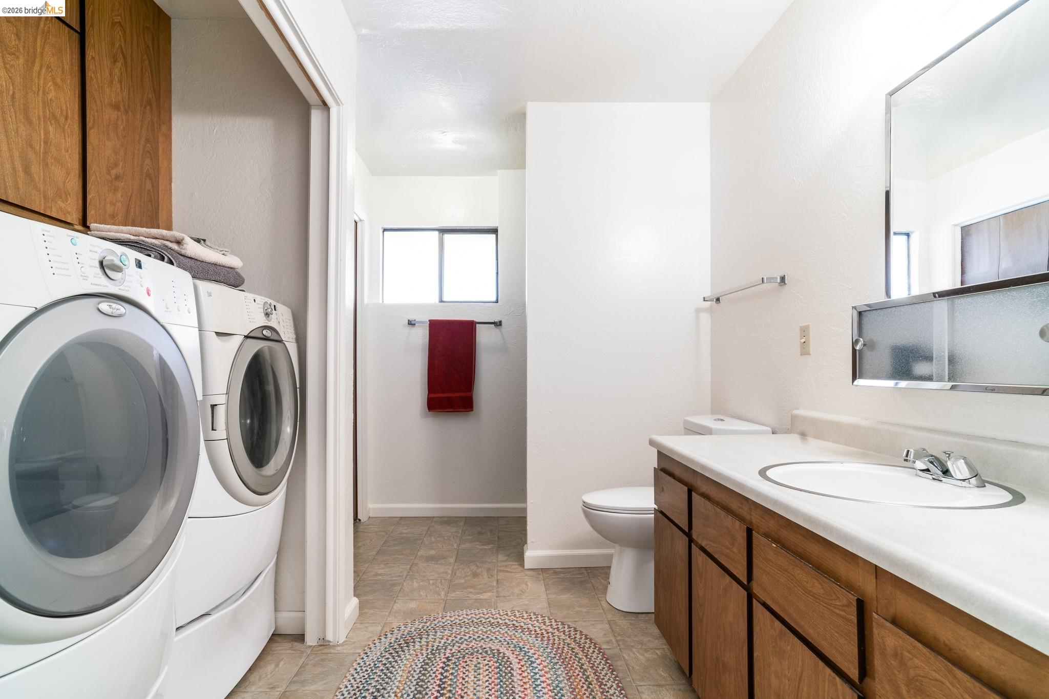 19711 Pleasantview Drive Groveland, CA 95321 - Photo 31 of 39 Dedicated laundry area featuring a washer and dryer, adjacent to a bathroom with a wood-finish vanity, integrated sink, and wall-mounted mirror