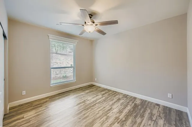 an empty room with windows and fan