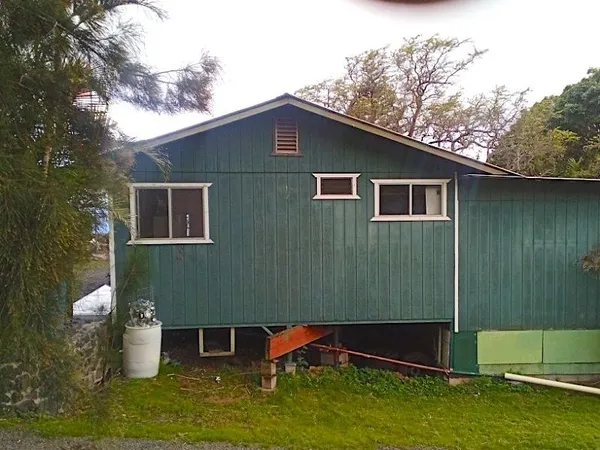 a backyard of a house with large trees and wooden fence