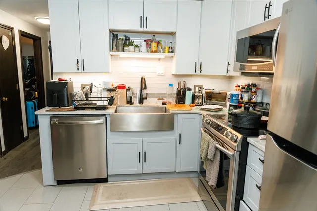 a kitchen with stainless steel appliances granite countertop a refrigerator sink stove and white cabinets