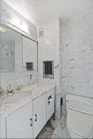 a bathroom with a granite countertop toilet sink and mirror