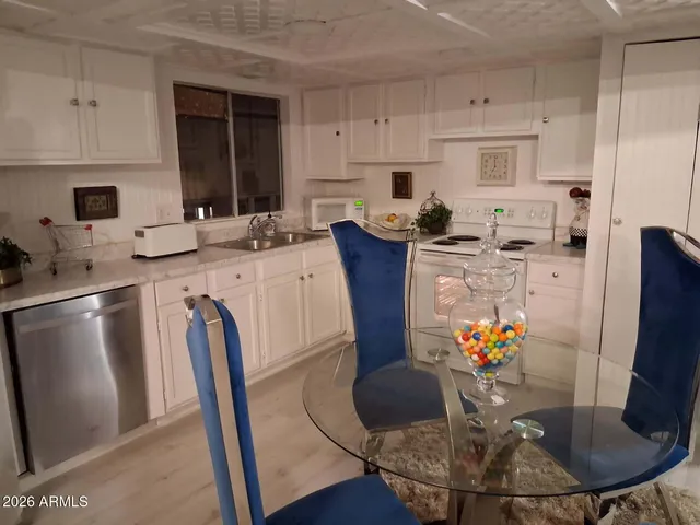 a kitchen with stainless steel appliances granite countertop a dining table chairs and a refrigerator