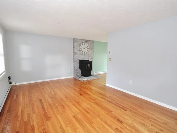 a view of empty room with wooden floor and fireplace