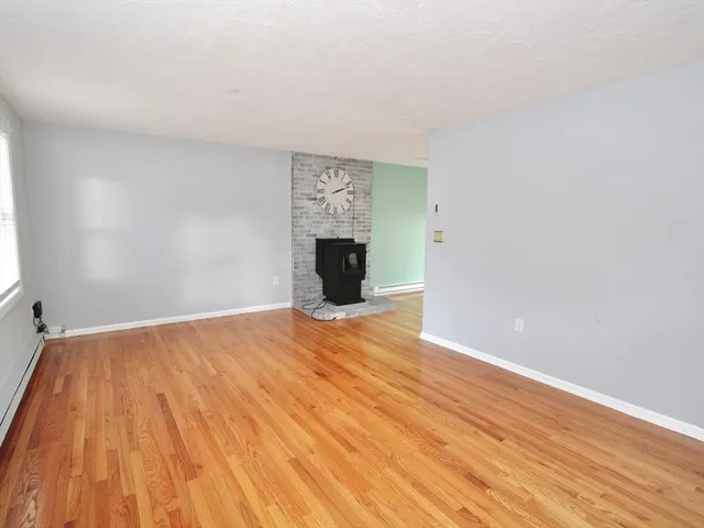 a view of empty room with wooden floor and fireplace
