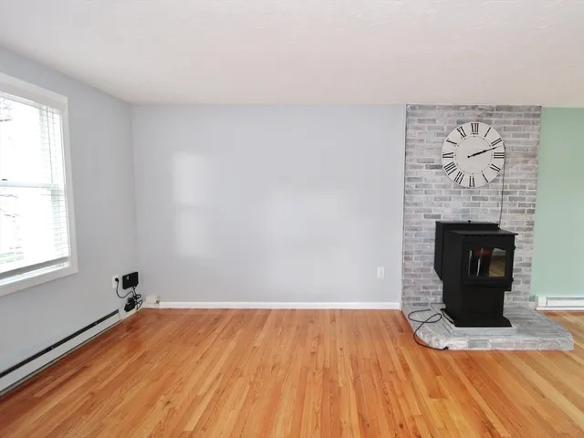 a view of empty room with wooden floor and fireplace