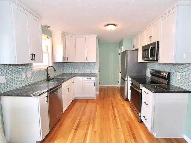 a large kitchen with stainless steel appliances granite countertop a lot of counter space and wooden floors