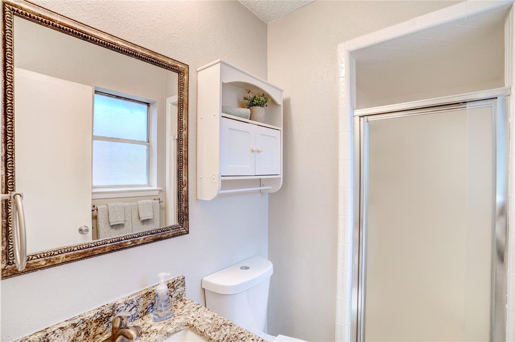 6028 Ridgecrest Drive Watauga, TX 76148 - Photo 22 of 40 a bathroom with a granite countertop sink mirror vanity and toilet