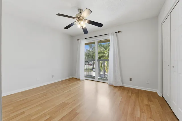 an empty room with wooden floor chandelier fan and windows