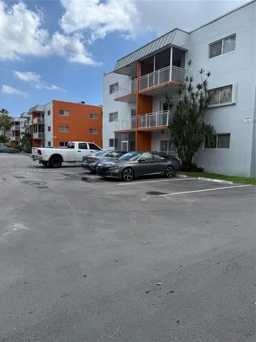 a city street lined with parked cars front of buildings
