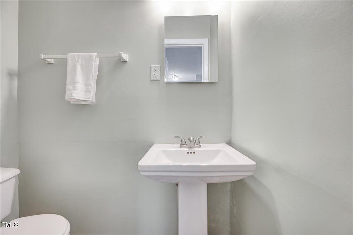 4808 Blue Bird Court, Unit D Raleigh, NC 27606 - Photo 13 of 31 a bathroom with a sink a mirror and toilet