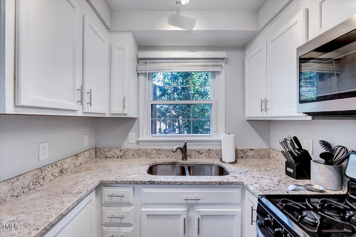 4808 Blue Bird Court, Unit D Raleigh, NC 27606 - Photo 15 of 31 a kitchen with stainless steel appliances granite countertop white cabinets sink and stove