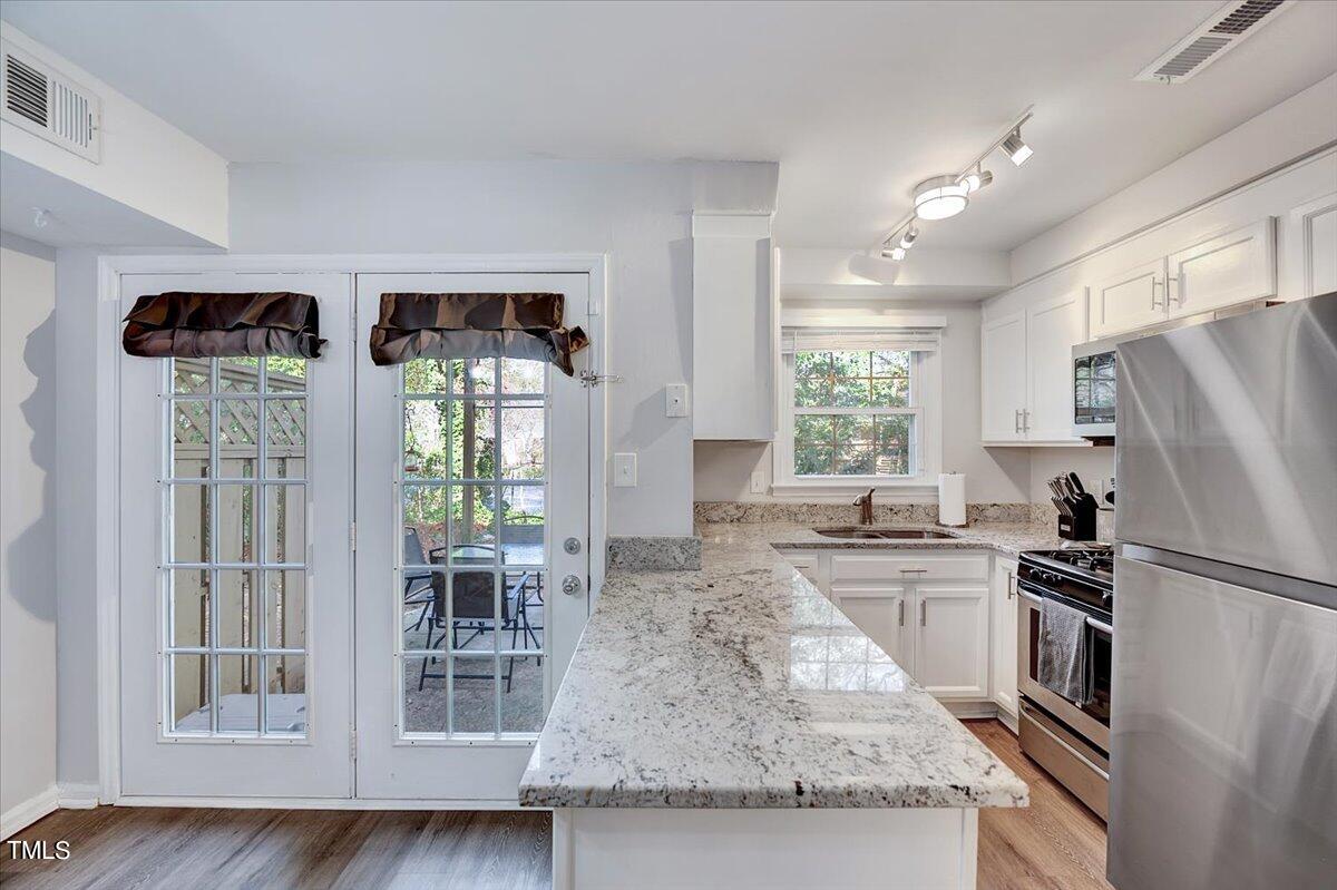 4808 Blue Bird Court, Unit D Raleigh, NC 27606 - Photo 16 of 31 a kitchen with stainless steel appliances granite countertop a refrigerator a stove a sink dishwasher and wooden cabinets with wooden floor