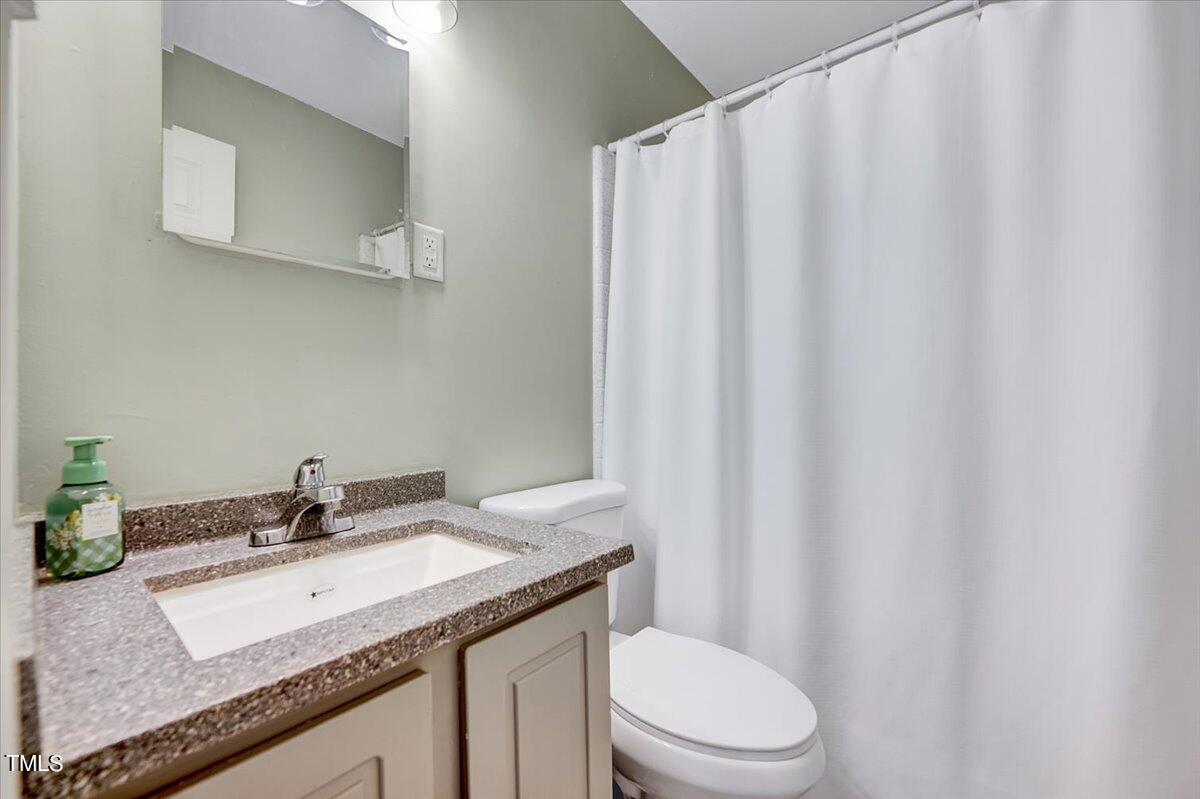 4808 Blue Bird Court, Unit D Raleigh, NC 27606 - Photo 19 of 31 a bathroom with a granite countertop sink toilet and a mirror
