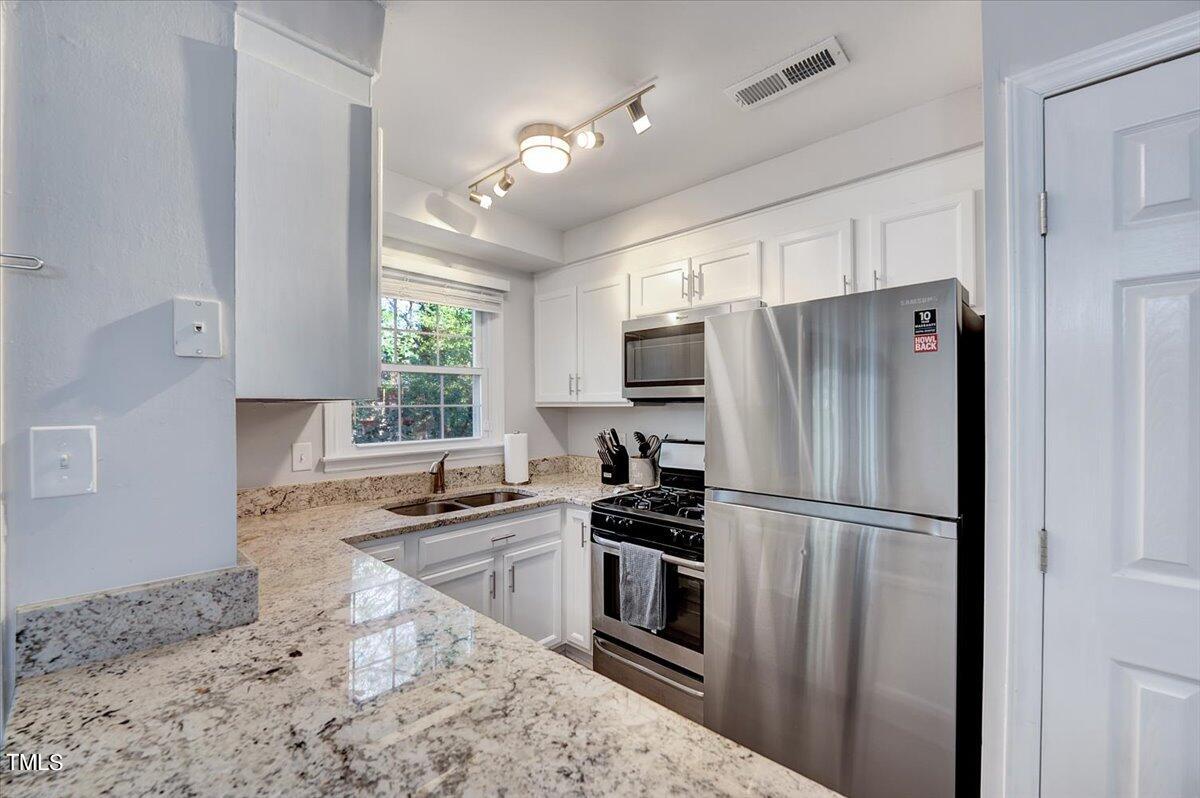 4808 Blue Bird Court, Unit D Raleigh, NC 27606 - Photo 2 of 31 a kitchen with granite countertop a refrigerator a sink stainless steel appliances and cabinets