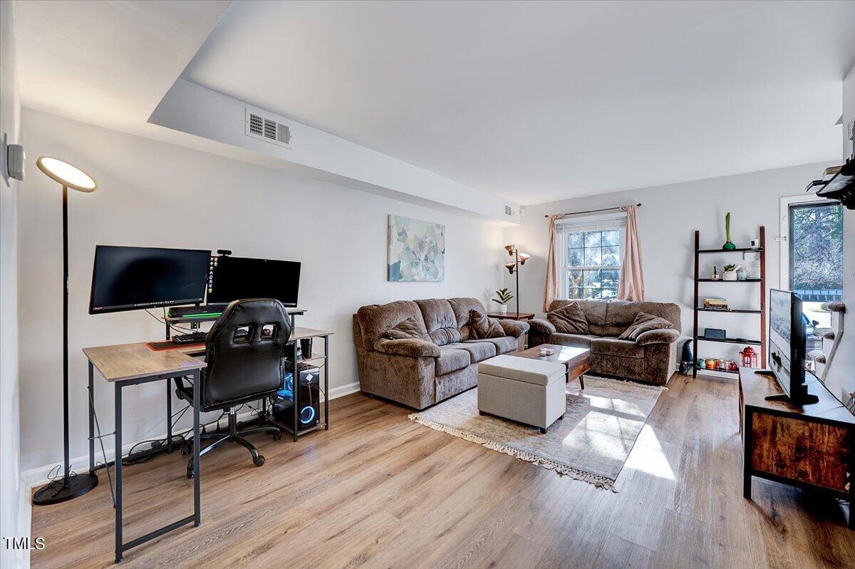 4808 Blue Bird Court, Unit D Raleigh, NC 27606 - Photo 8 of 31 a living room with furniture a wooden floor and a flat screen tv