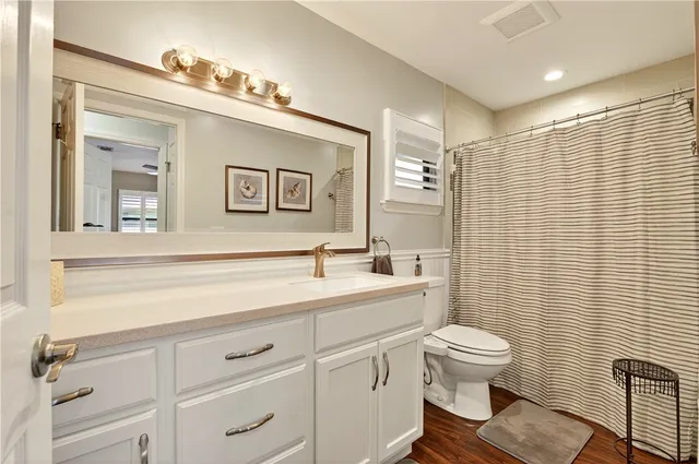 a bathroom with a toilet sink vanity and mirror