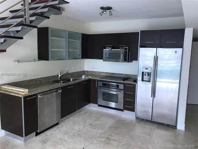 a kitchen with stainless steel appliances granite countertop a refrigerator and a stove