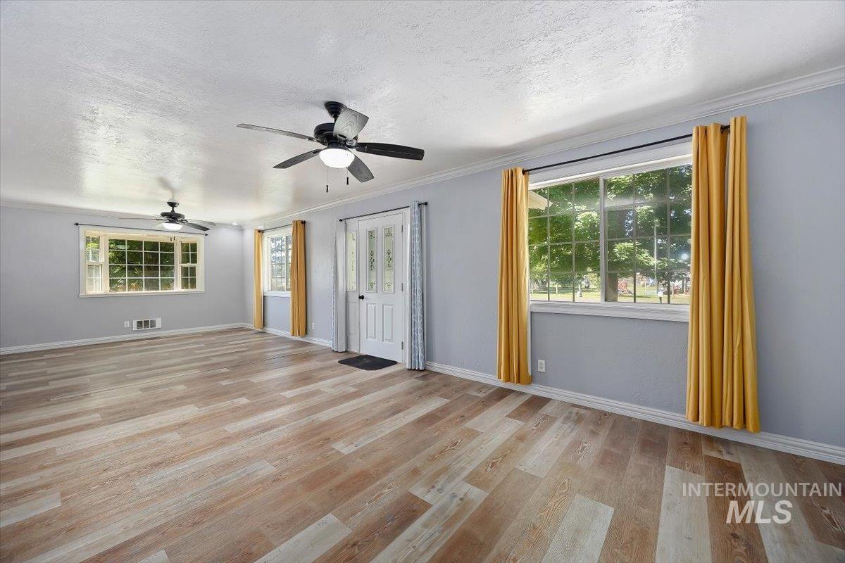 1940 Q Street Heyburn, ID 83336 - Photo 6 of 30 Spacious interior with wood-finish flooring, light grey walls, and white crown molding