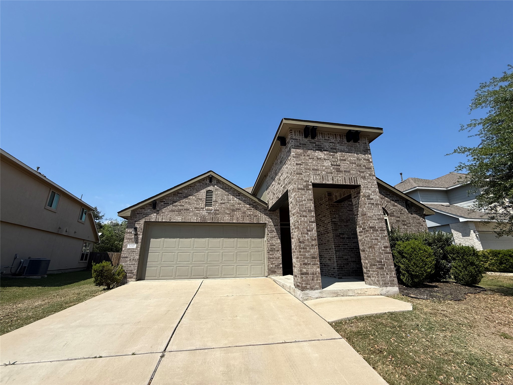 View of front of home featuring brick siding, an attached garage, driveway, and a front lawn