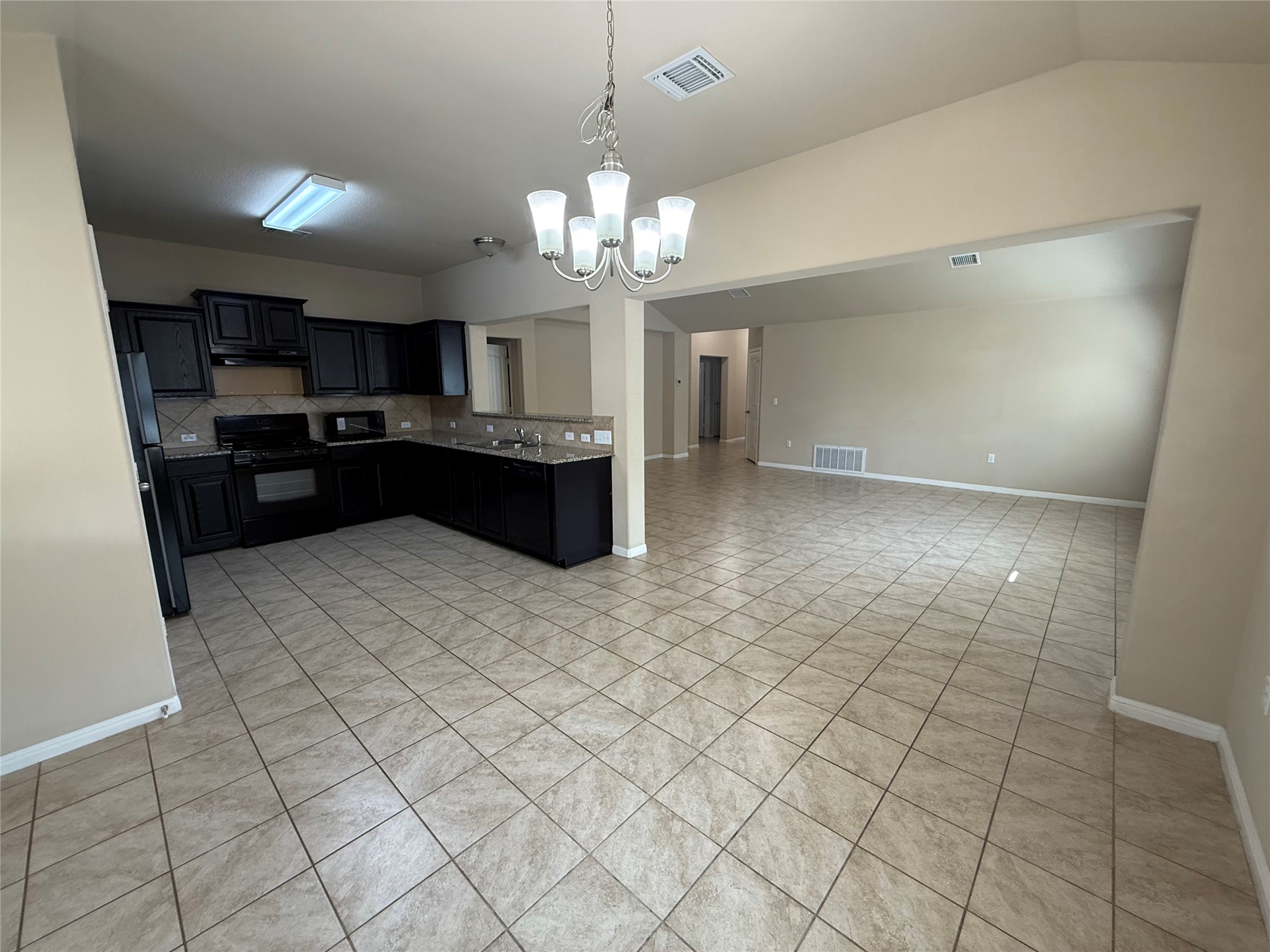1441 Hamiltons Way Leander, TX 78641 - Photo 20 of 20 Kitchen featuring dark cabinets, a chandelier, black appliances, open floor plan, and light tile patterned floors