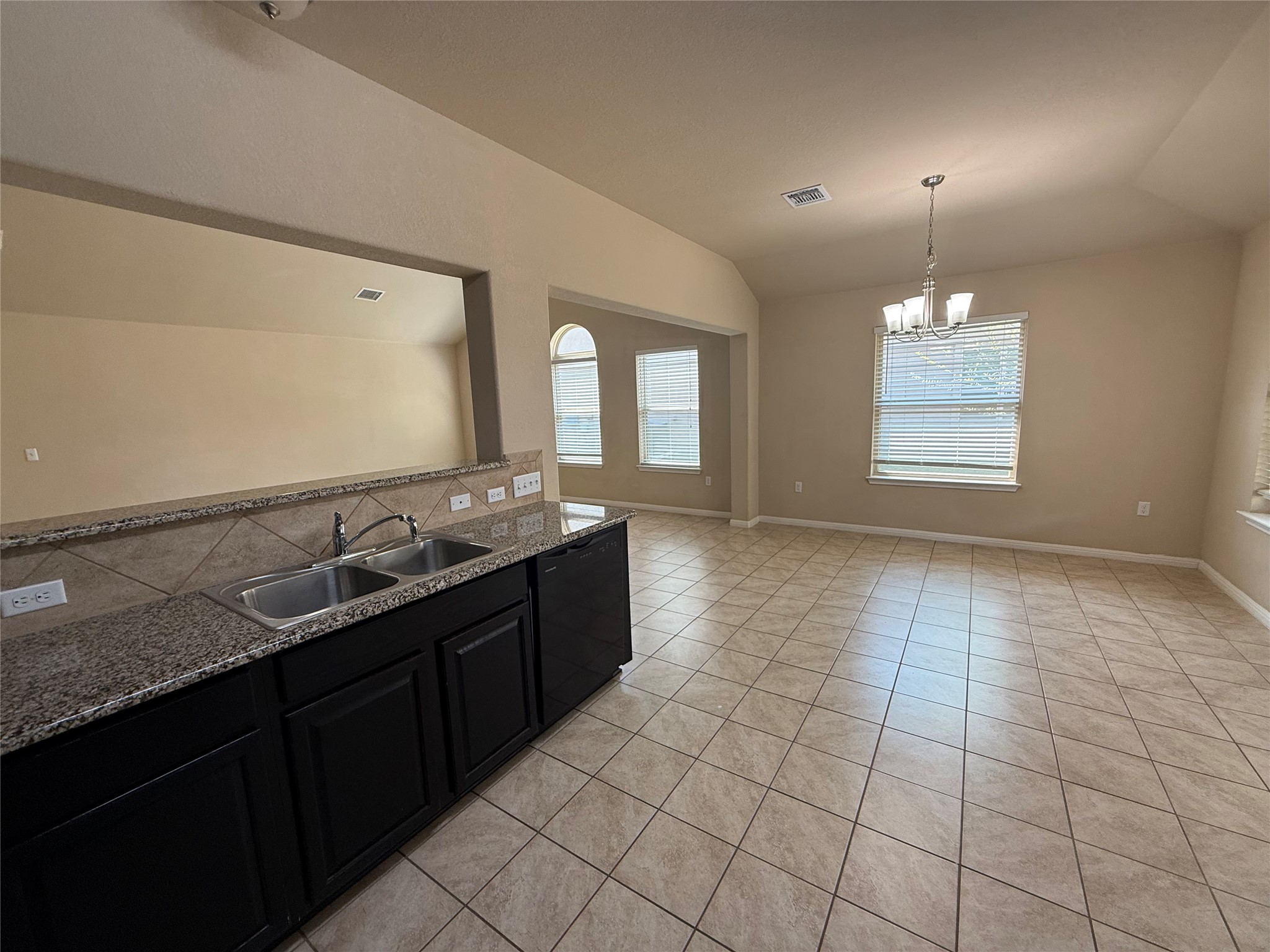 1441 Hamiltons Way Leander, TX 78641 - Photo 17 of 20 Kitchen with dark cabinetry, black dishwasher, light tile patterned floors, hanging lights, and vaulted ceiling