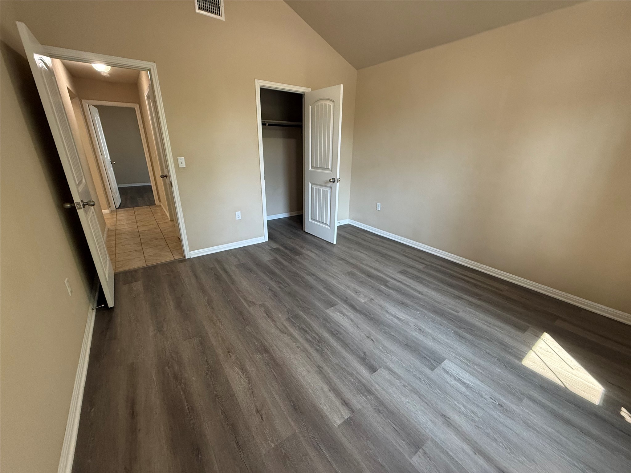 1441 Hamiltons Way Leander, TX 78641 - Photo 2 of 20 Unfurnished bedroom featuring vaulted ceiling, dark wood finished floors, and a closet