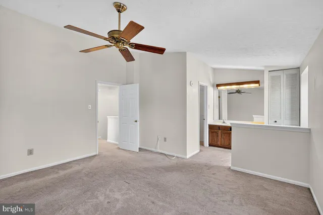 a view of empty room with wooden floor and ceiling fan