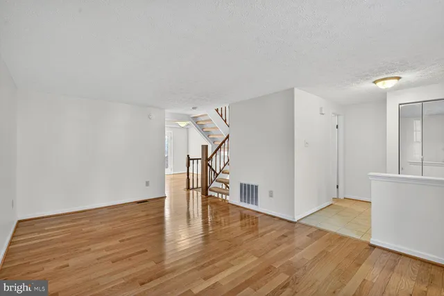 a view of empty room with wooden floor and stairs