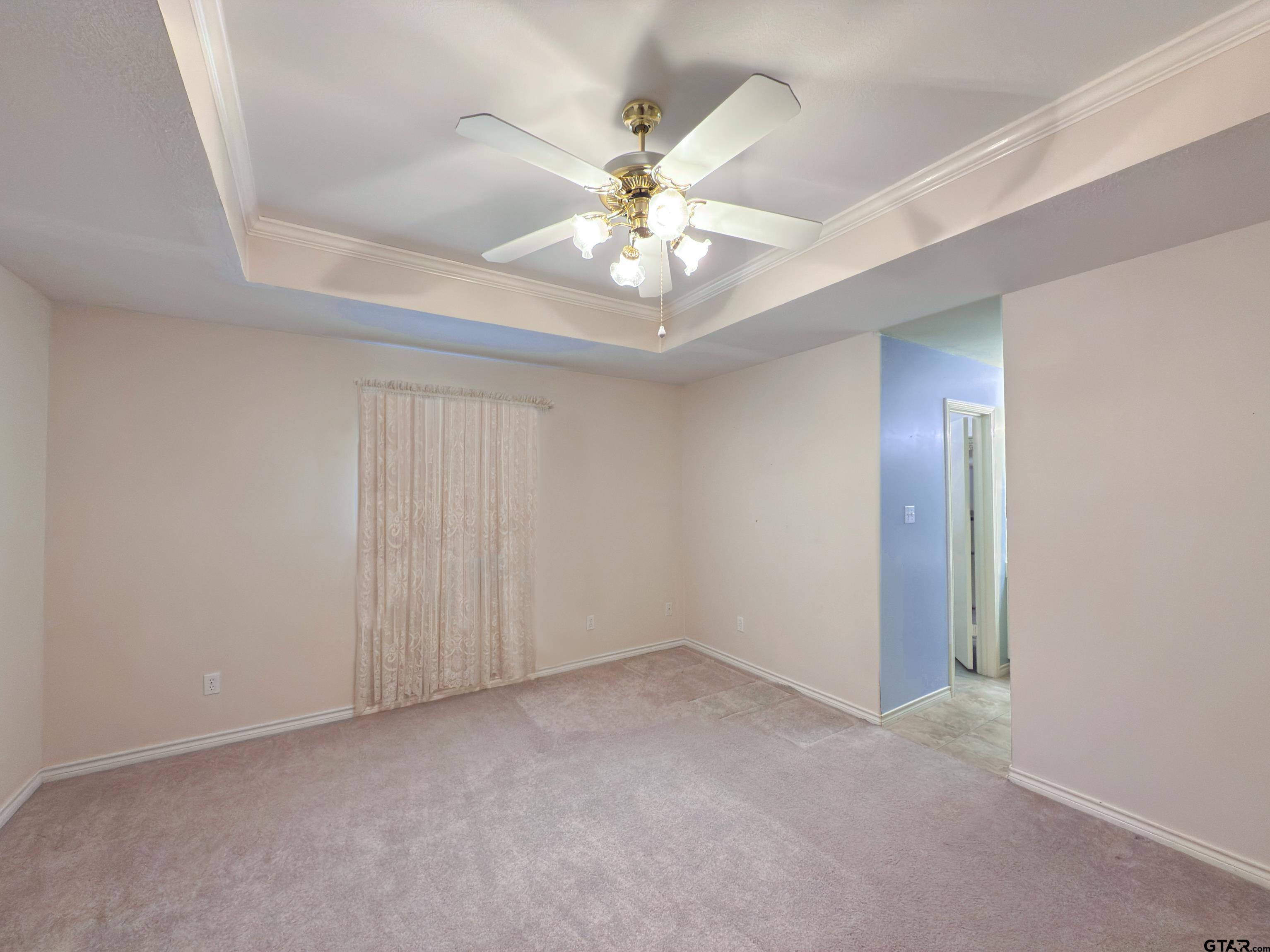1202 Rice Road, Unit 112 Tyler, TX 75703 - Photo 6 of 12 an empty room with a chandelier fan and windows