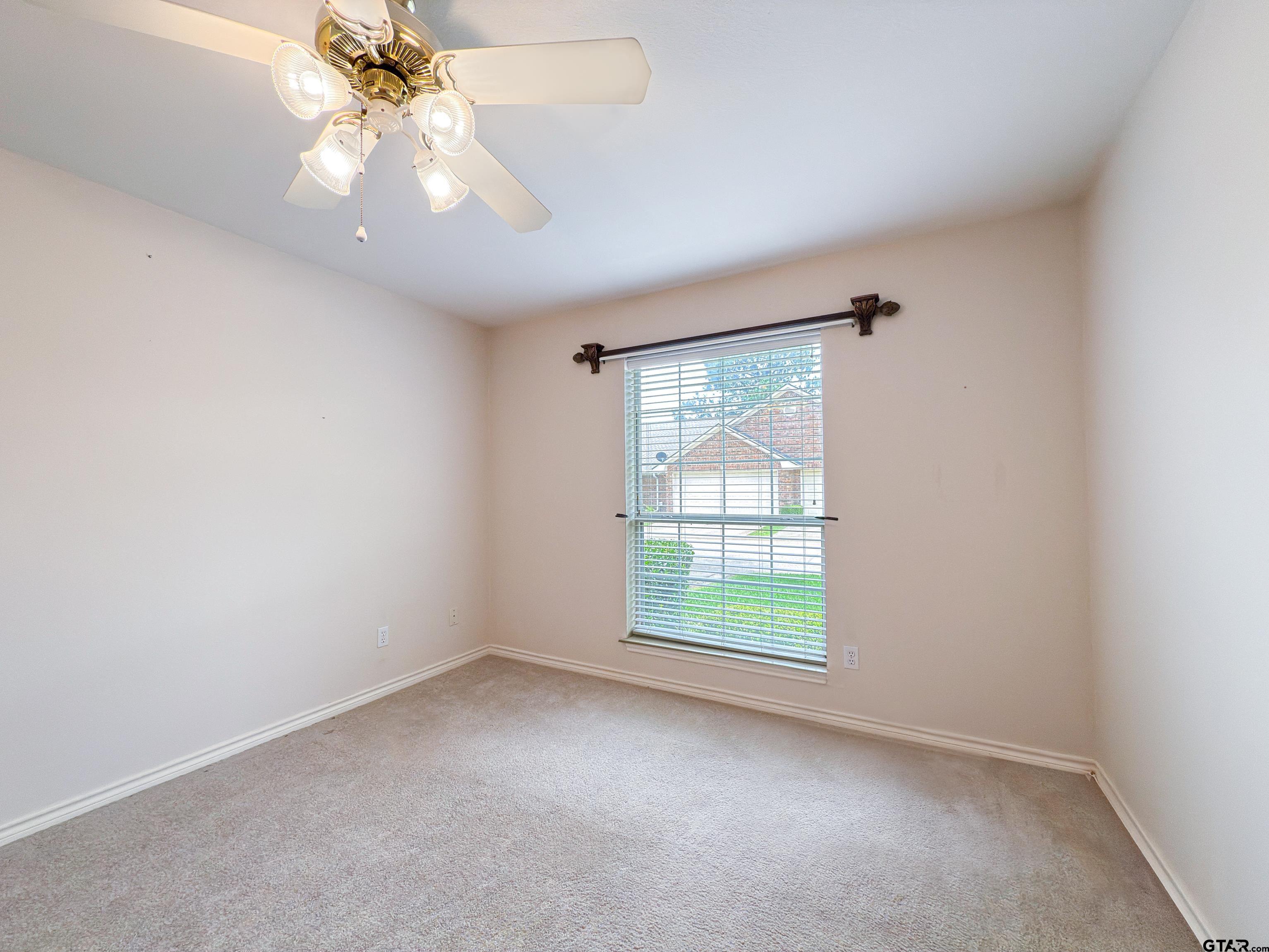 1202 Rice Road, Unit 112 Tyler, TX 75703 - Photo 10 of 12 an empty room with a window and a fan