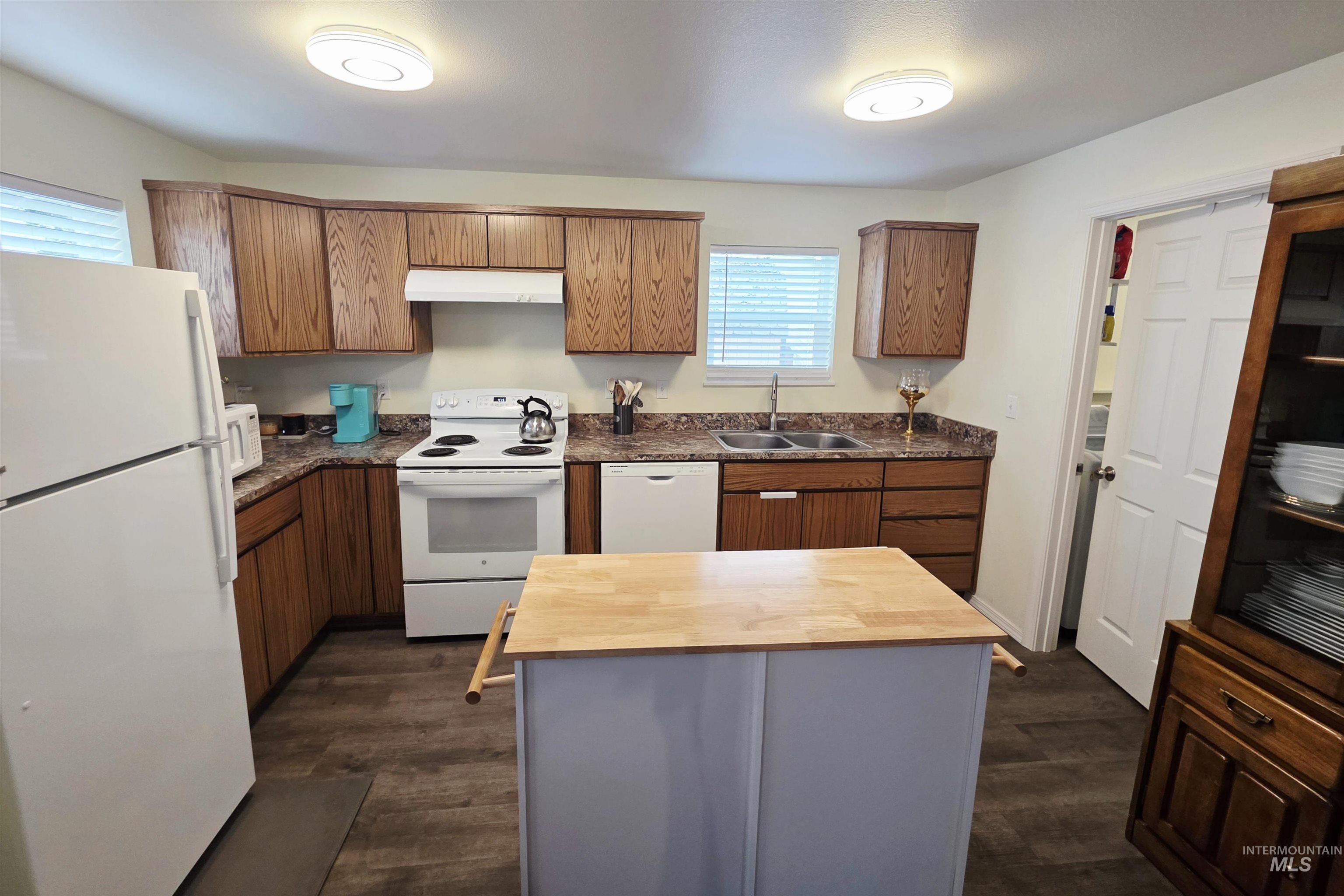 409 8th Street Clarkston, WA 99403 - Photo 4 of 23 Kitchen featuring wood-finish cabinetry, dark countertops, a double basin sink, and wood-finish flooring