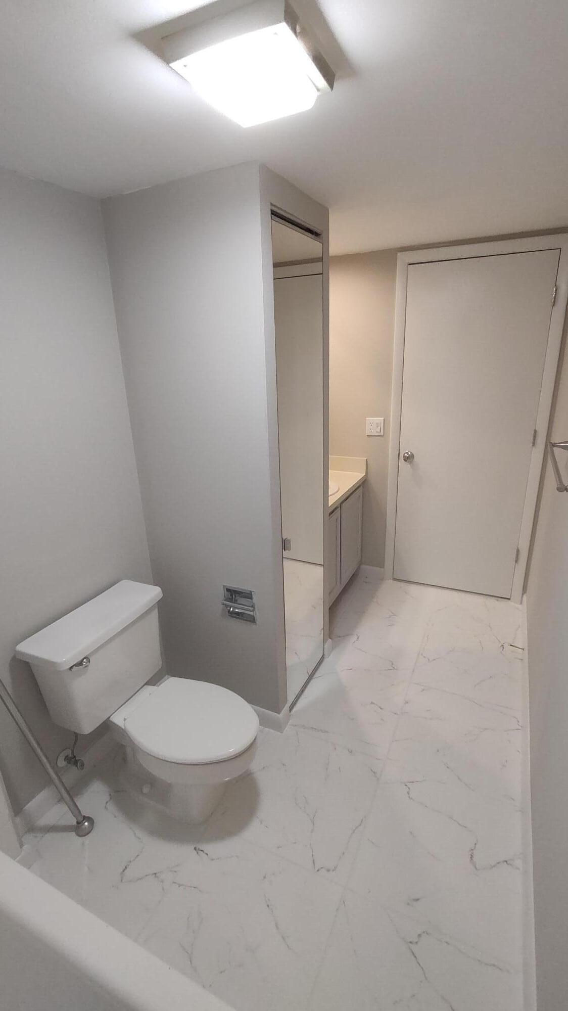 5646 Southeast Windsong Lane, Unit 415 Stuart, FL 34997 - Photo 13 of 20 a bathroom with a toilet and a sink