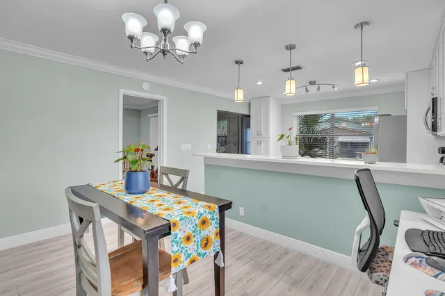 a dining room with wooden floor a chandelier a wooden table and chairs