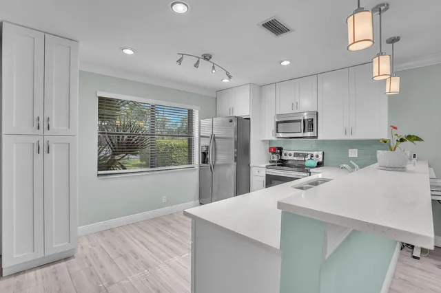 a kitchen with kitchen island a counter top space a sink stainless steel appliances and cabinets