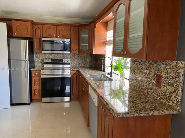 a kitchen with stainless steel appliances granite countertop a stove a sink and a refrigerator