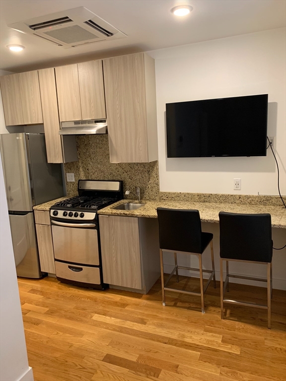 21 5th Street, Unit 20 Chelsea, MA 02150 - Photo 2 of 12 a kitchen with stainless steel appliances a stove a microwave a sink and white cabinets