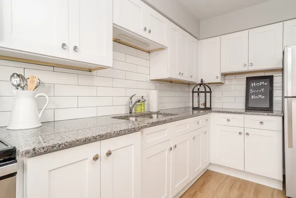 a kitchen with granite countertop white cabinets and white appliances