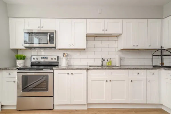 a kitchen with granite countertop white cabinets and stainless steel appliances