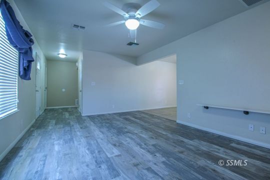 1043 Peg Street Ridgecrest, CA 93555 - Photo 6 of 45 an empty room with wooden floor chandelier fan and windows