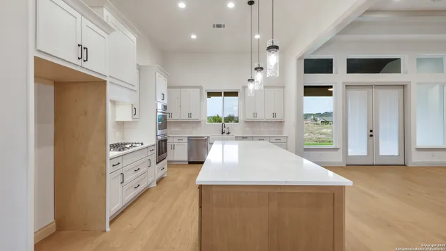 a large kitchen with stainless steel appliances kitchen island granite countertop a refrigerator and a sink